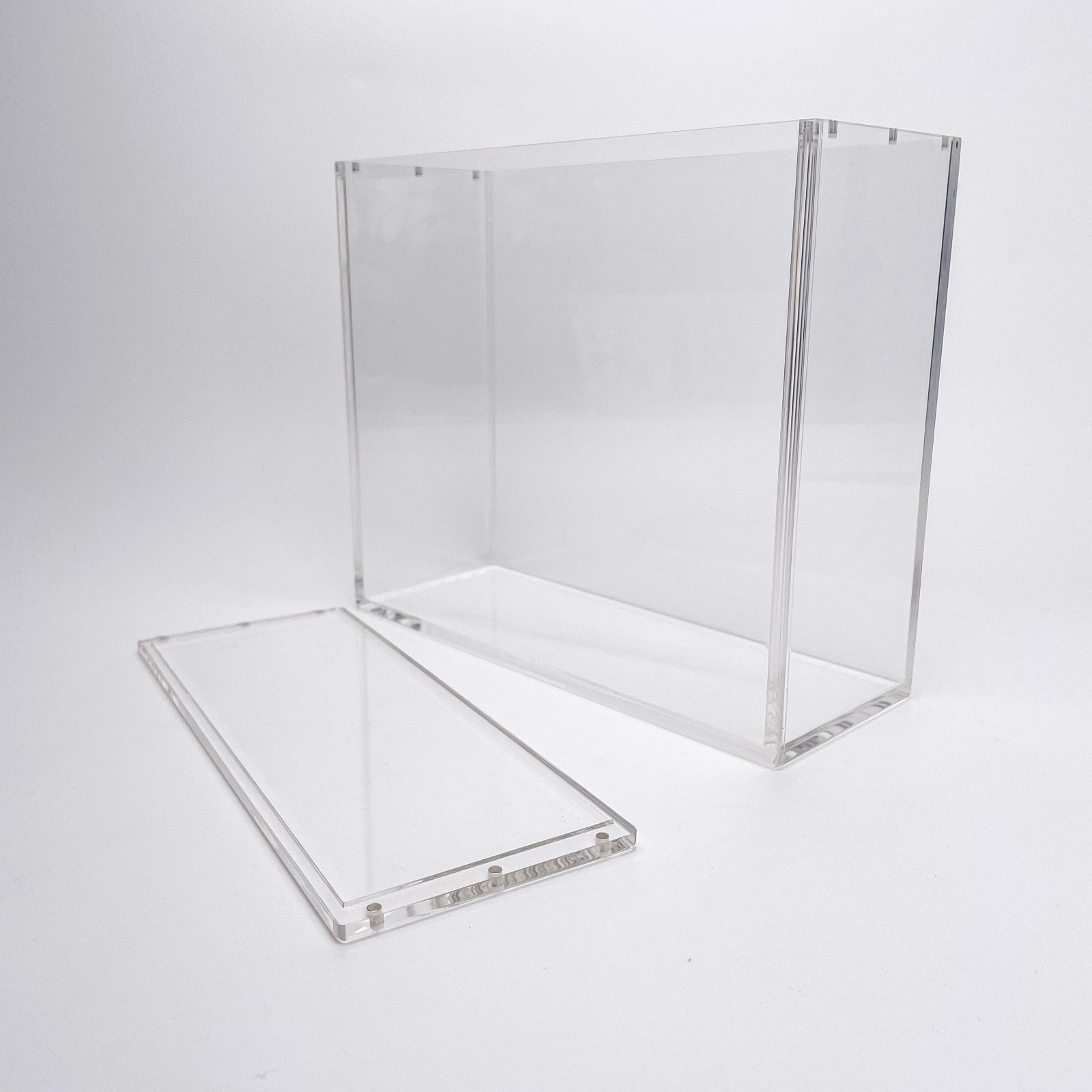 Clear acrylic display case for TCG booster boxes with a magnetic, removable top lid on a white background.