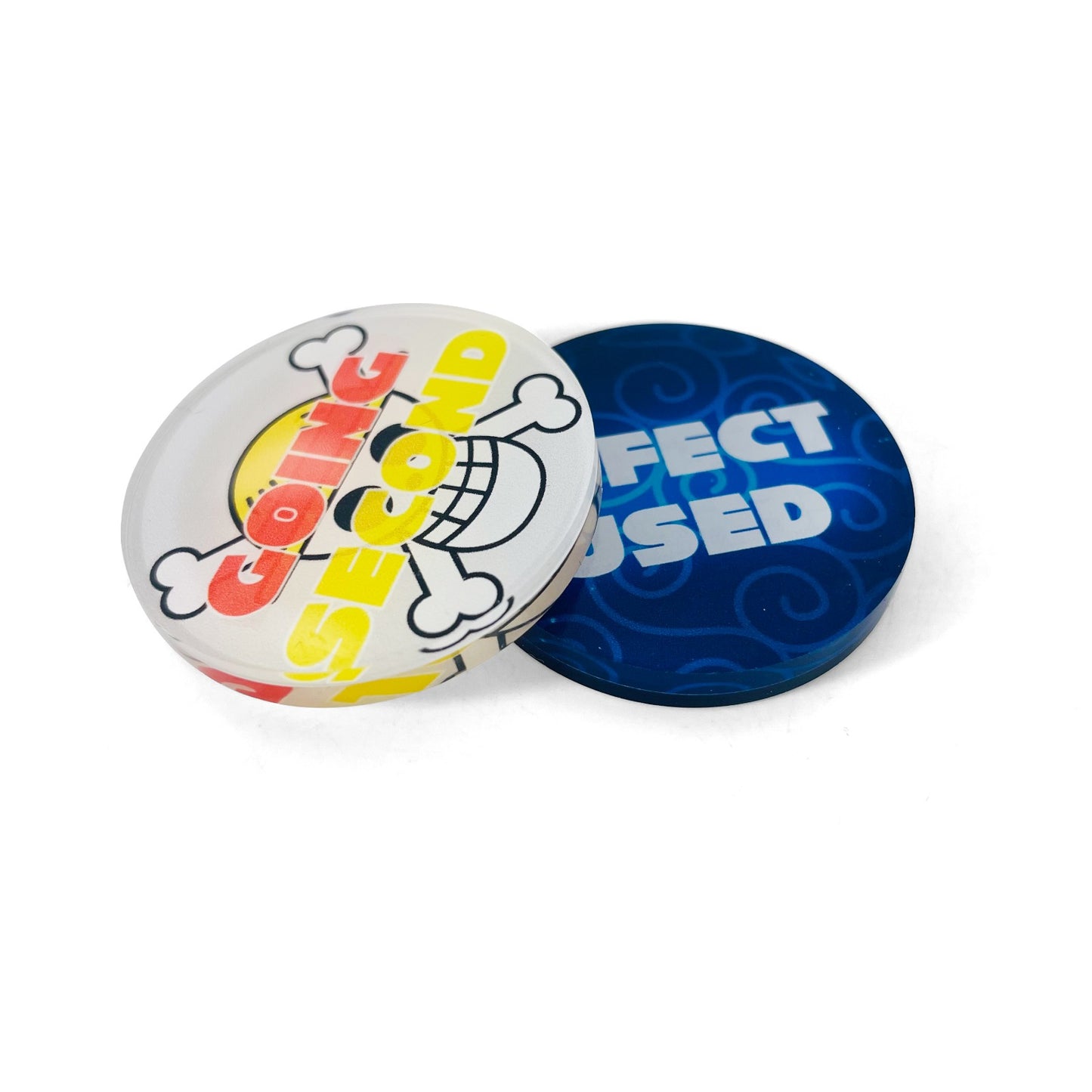 Two round acrylic One Piece Card Game tokens: one white with a skull logo and "Going Second," one blue with "Effect Used.