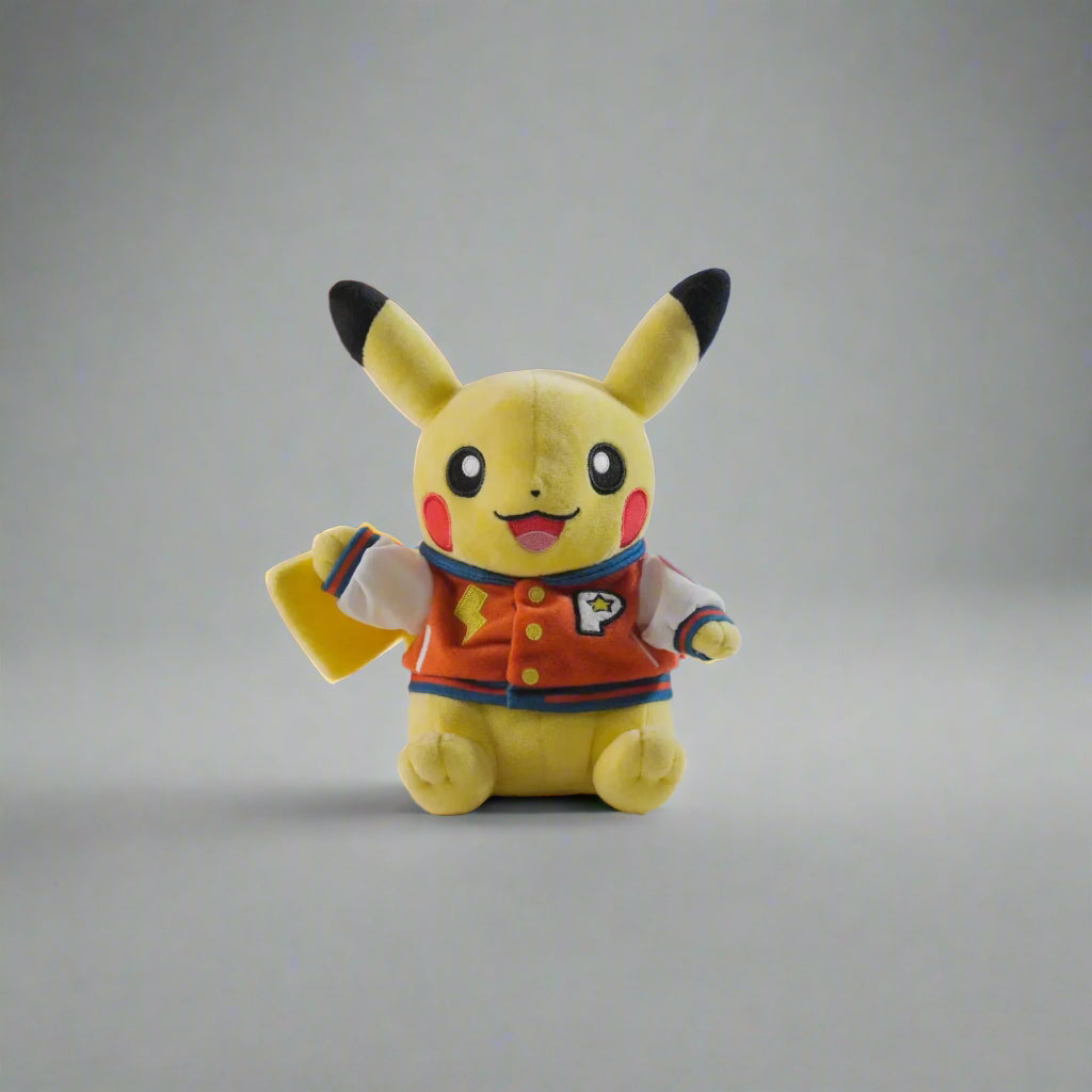 Soft yellow Pikachu plush wearing a red and white varsity jacket with a lightning bolt and P logo on a gray background.