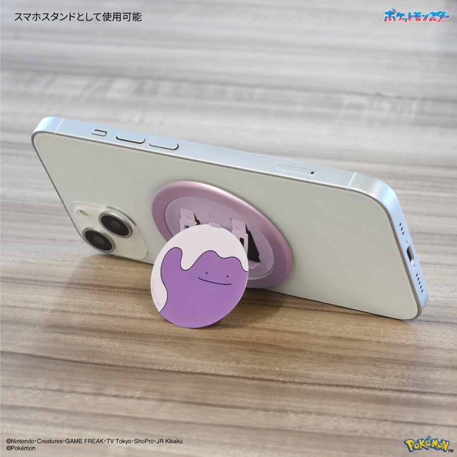Purple Ditto Pokémon CHIP-POP magnetic phone grip and stand attached to the back of a smartphone on a wooden surface.