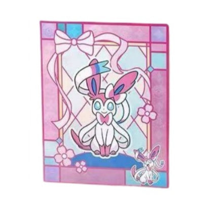 Pokémon card binder featuring a pink and blue stained-glass design with Sylveon, a bow, and floral accents.