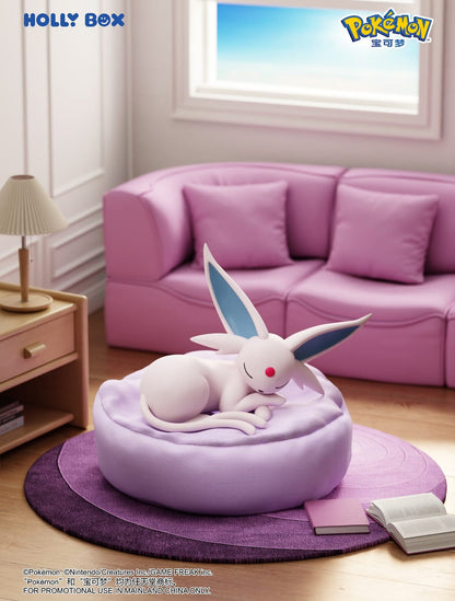 Espeon sleeping on a soft, round purple beanbag cushion in a cozy room with a pink sofa and wooden side table.