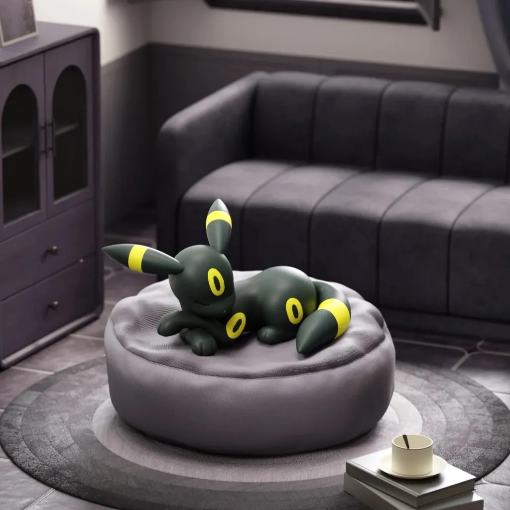 Umbreon sleeping figure in black and yellow resting on a soft, grey circular beanbag cushion.