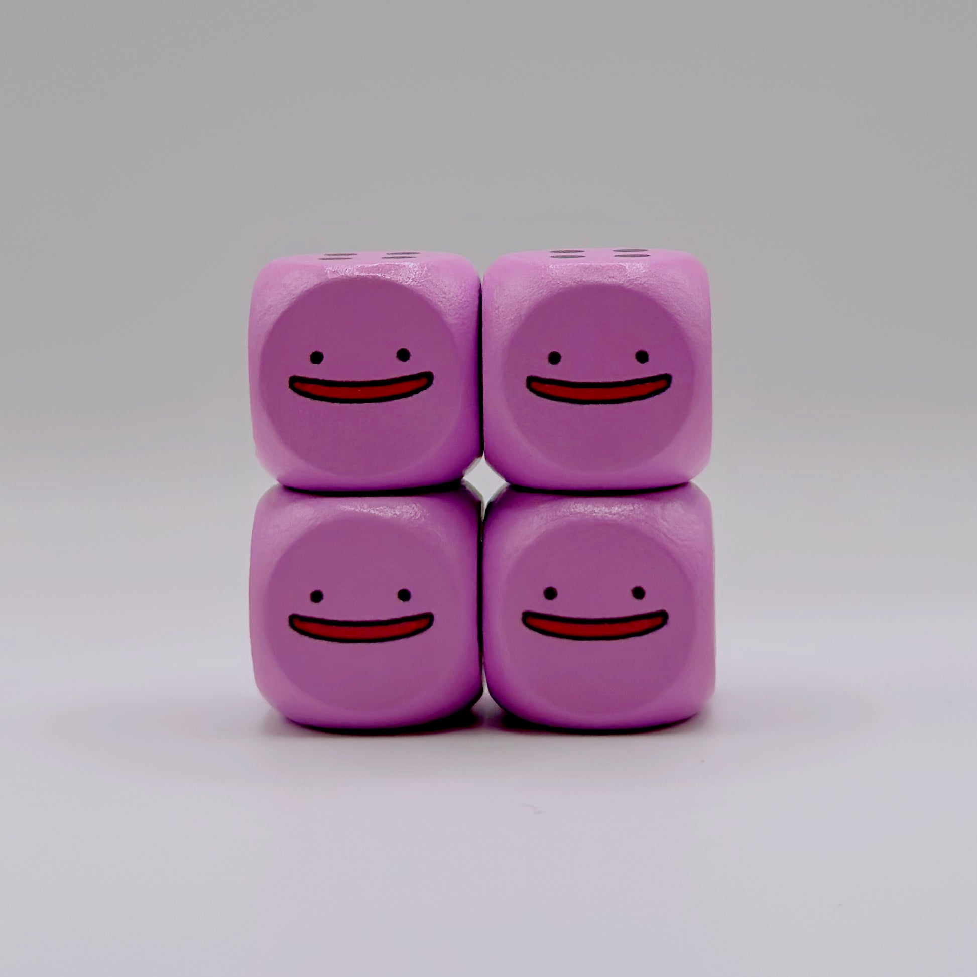 Four light purple 16mm wooden TCG dice with rounded corners and a custom smiling face design on the number one side.