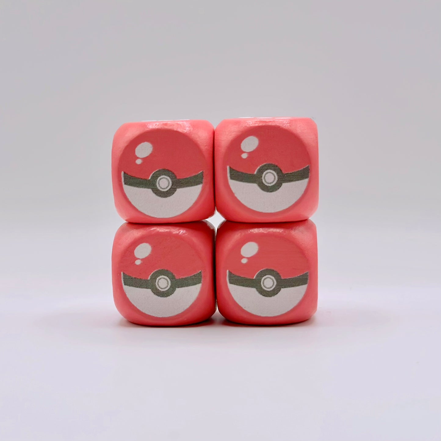 Four 16mm pink wooden dice with custom UV-ink Poké Ball designs on the number one side, featuring rounded corners.