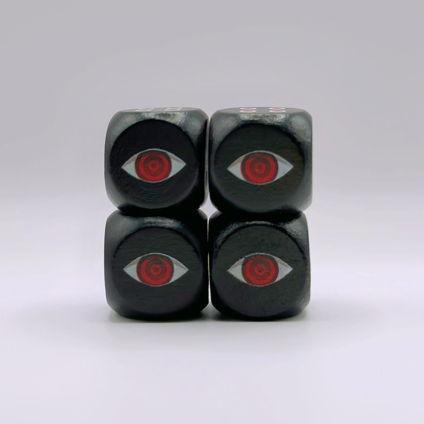Four 16mm black wooden dice featuring a custom red eye design on the one-side, engraved with detailed UV-ink.