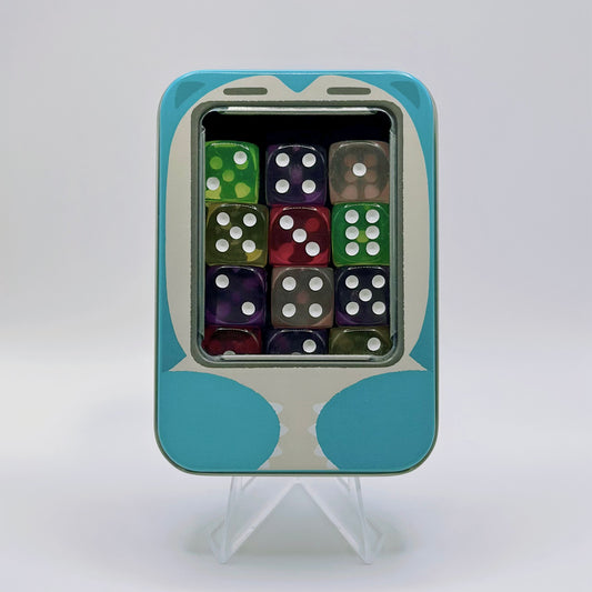 Blue metal TCG dice tin with a snoring character design, featuring an inner foam insert holding 12 colorful dice.