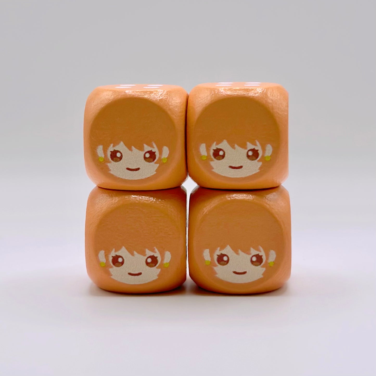 Four 16mm orange wooden TCG dice with rounded corners and a custom anime-style character face engraved on the one side.