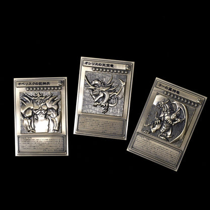 Three zinc alloy Yu-Gi-Oh! Egyptian God relief cards in silver, featuring Obelisk, Slifer, and Ra.